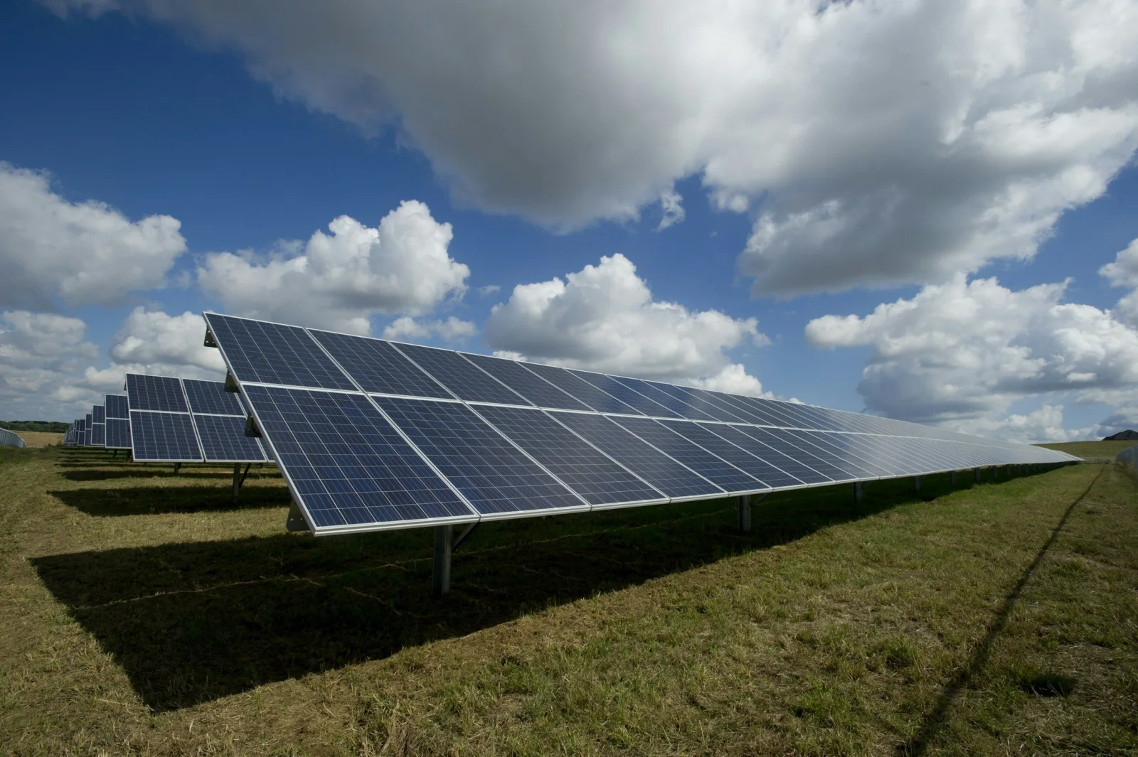 Photovoltaic panels beneath a broad, cloud-filled sky